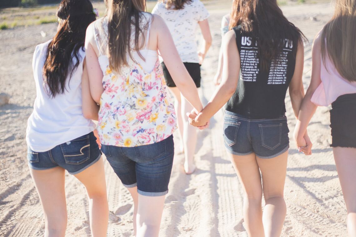 Young women walking away from the camera holding hands