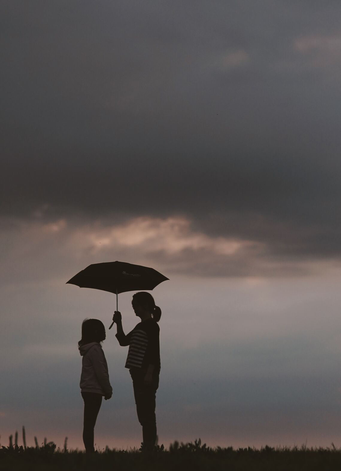 A woman holding an umbrella over a young girl