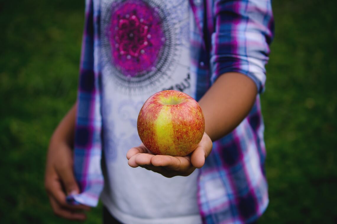 A teenager holding an apple
