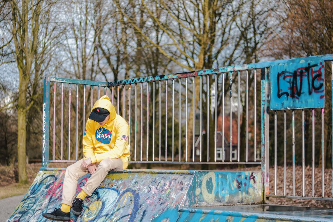 A young man sitting on a skateboard ramp 