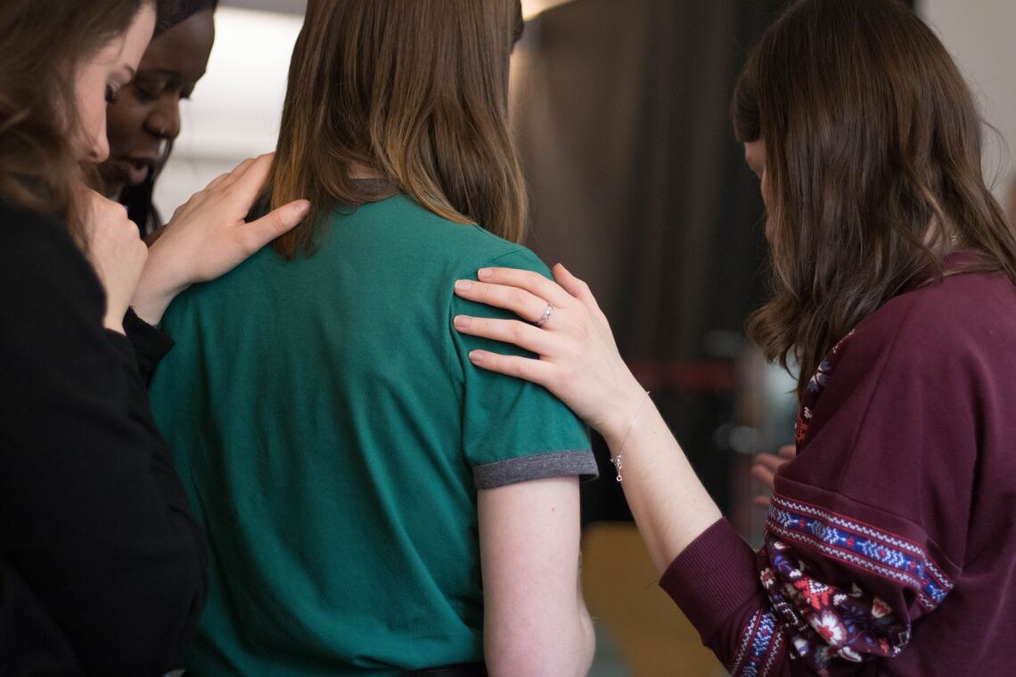 Three girls comforting another girl